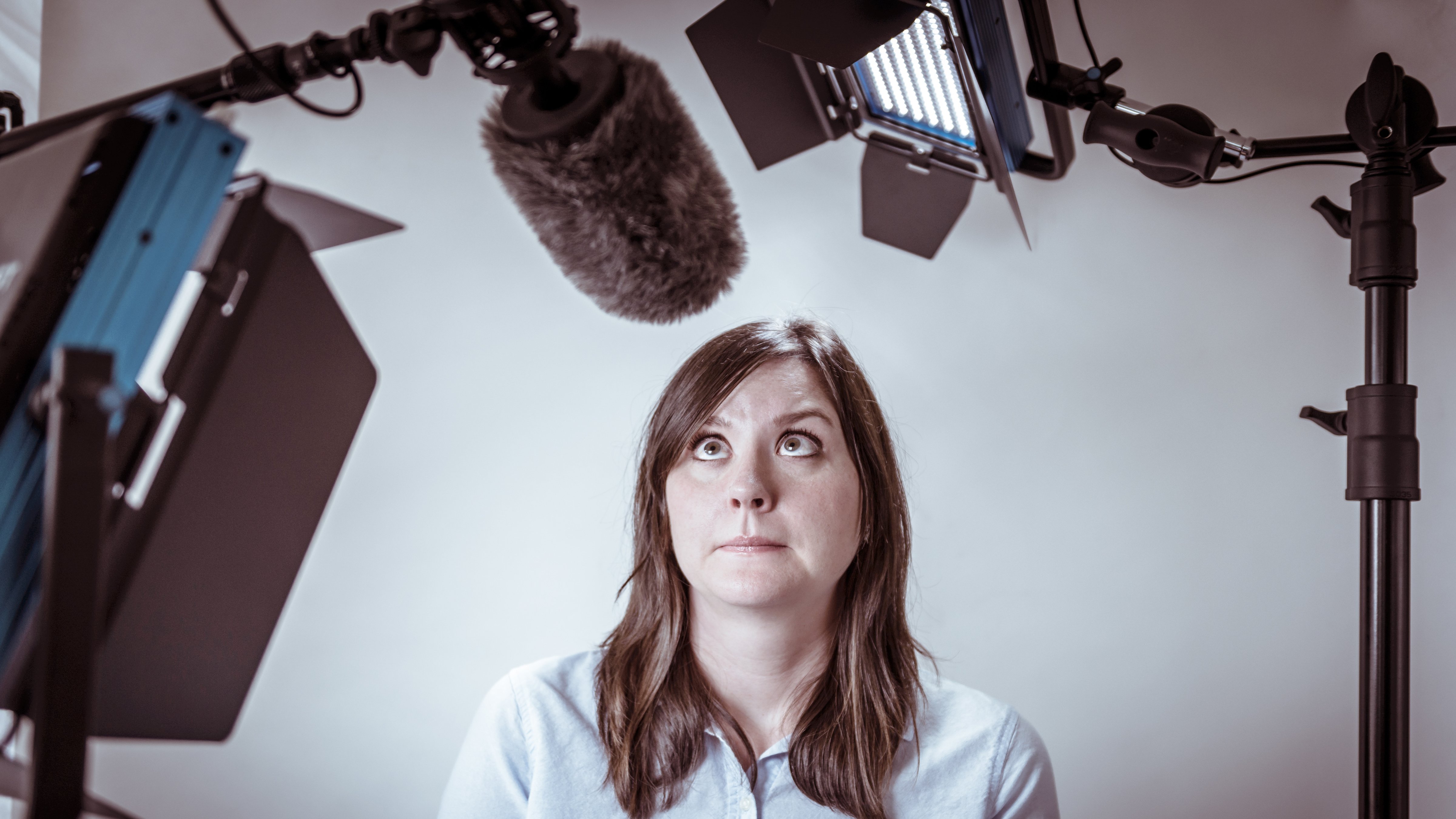 Woman on a video production set looks worriedly up at microphone boom